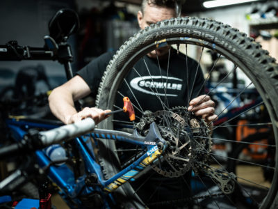 Técnico ajustando la rueda trasera de una bicicleta de montaña en un taller especializado.